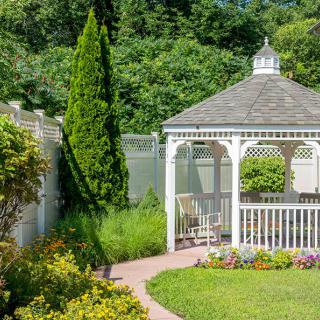 A charming gazebo surrounded by lush greenery and colorful flowers in a serene garden setting.
