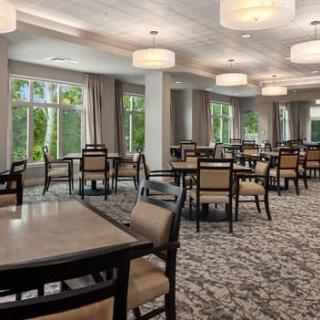 Elegant dining room with multiple tables, chairs, and large windows offering a view of the outdoors.
