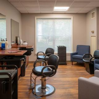 A well-lit hair salon interior featuring styling chairs, mirrors, and a waiting area with comfortable seating.