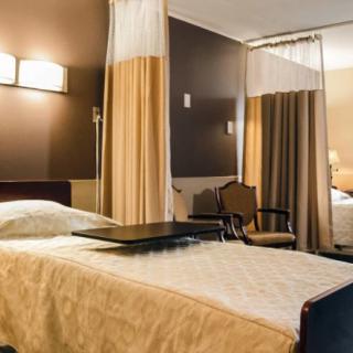 A well-lit hospital room with a bed and privacy curtains.