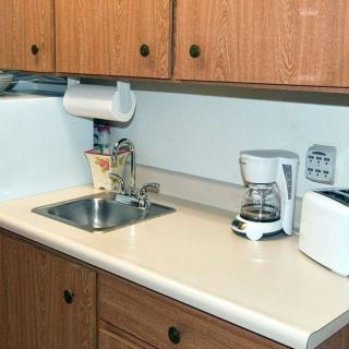 A kitchen with wooden cabinets, featuring a sink, coffee maker, and toaster on the countertop.