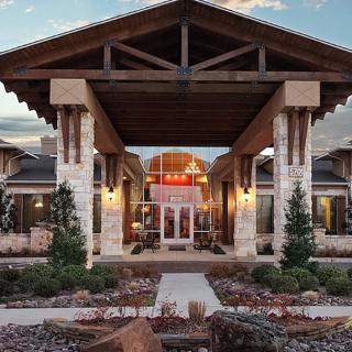 Modern building entrance with stone columns and landscaped surroundings.