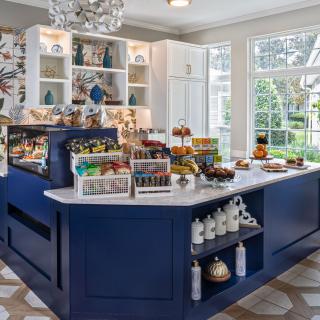 A quaint cafe interior featuring a central blue counter displaying an assortment of desserts and snacks.