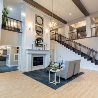 Spacious and modern living room with high ceilings, featuring a fireplace and an elegant staircase.