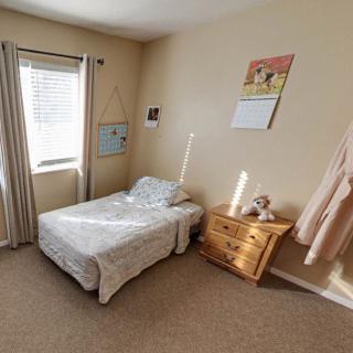 A minimalist bedroom with a single bed, nightstand, and window with curtains.