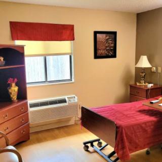 A cozy bedroom with a single bed, dresser, and lamp.