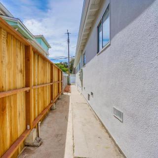 A narrow outdoor pathway next to a house, bordered by a wooden fence.