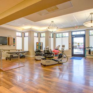 A bright and spacious rehabilitation gym featuring various exercise equipment, designed for promoting fitness and wellness.