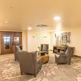 A cozy lobby seating area with chairs arranged around a table under warm lighting.