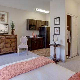 A cozy apartment with a bedroom and kitchenette area, featuring elegant furniture and decor.