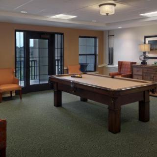 A cozy billiard room featuring a central pool table, comfortable seating, and tasteful decor.