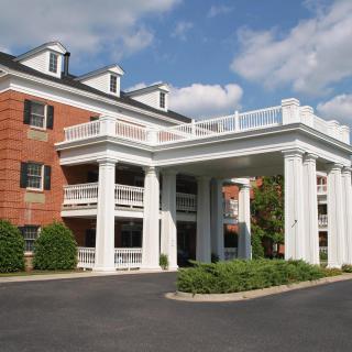 A grand hotel entrance with white columns under a partly cloudy sky.