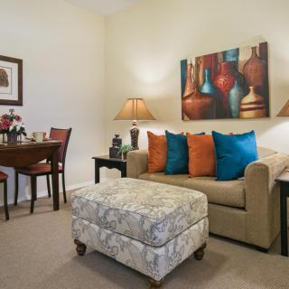 A cozy living room with a sofa, colorful cushions, and decorative artwork.