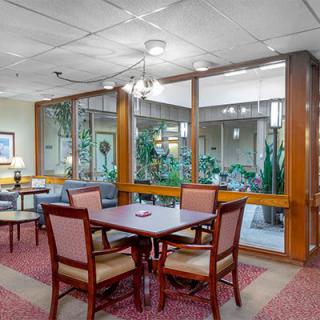 A cozy dining area with wooden furniture and glass windows overlooking an indoor garden.