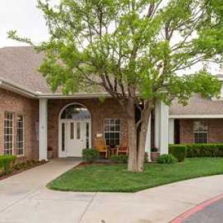 A brick building with a lush tree and a welcoming entrance path.