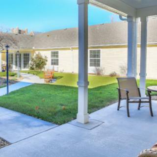A cozy patio with chairs overlooking a well-maintained lawn and garden area.