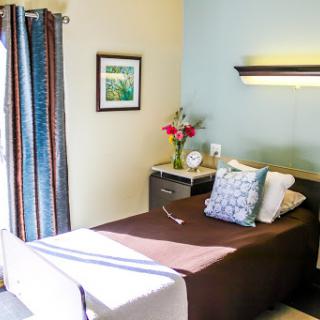 A cozy and well-decorated bedroom featuring a neatly made bed, colorful curtains, and decorative elements.