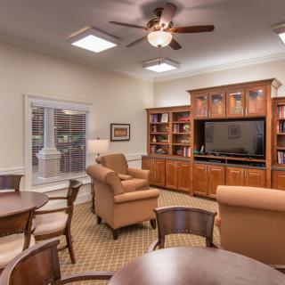 A cozy living room with armchairs, a television, and bookshelves.