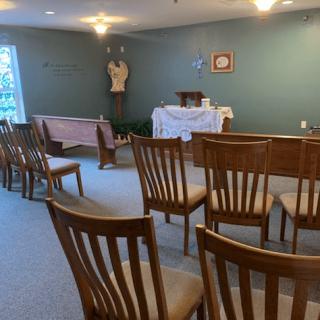 A small chapel with wooden chairs facing an altar, creating a peaceful and intimate worship space.
