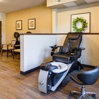 A salon interior featuring a pedicure chair and a cozy waiting area.