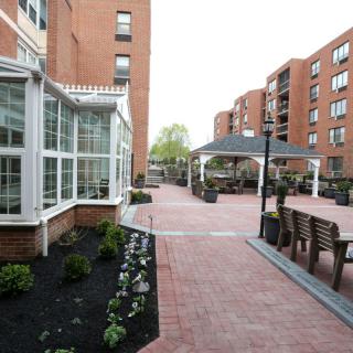 A well-maintained courtyard between apartment buildings featuring brick pathways and outdoor seating.