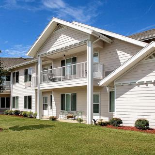 A two-story house with a balcony and well-maintained lawn under a blue sky.