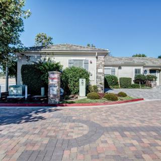 A suburban house with a well-maintained driveway and landscaping under a clear blue sky.