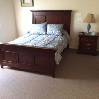 A neatly arranged bedroom with a wooden bed and matching nightstand.