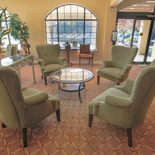 A cozy lobby seating area with armchairs and a glass table.
