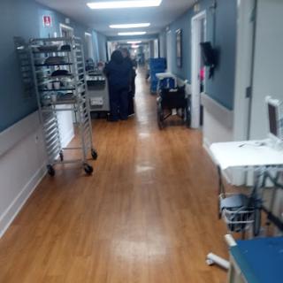 A corridor in a healthcare facility, featuring medical equipment and staff attending to patients.