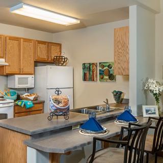 A cozy kitchen with wooden cabinets, a counter with bar stools, and various decorations.