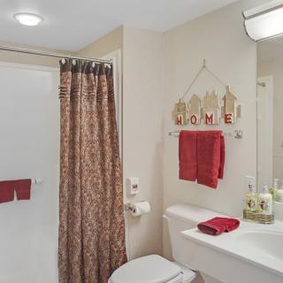 A neatly organized bathroom with red accents and decorative elements.