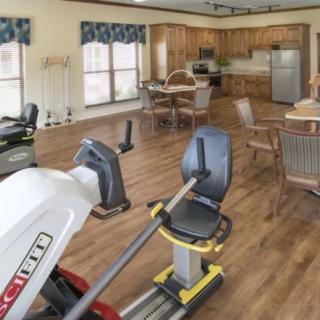 A multifunctional room with fitness equipment and a kitchen area.