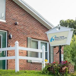 A brick building with a sign for a care center next to a white fence and greenery.