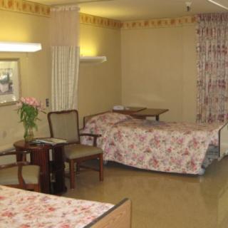 A hospital room with multiple beds and a small table.
