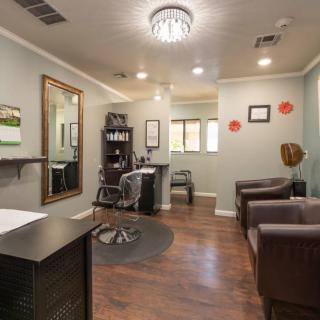 A well-lit salon interior featuring comfortable chairs, a large mirror, and stylish decor.