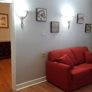 A cozy living room with a red couch and wall-mounted art pieces under warm lighting.