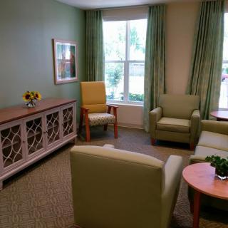 A cozy living room with comfortable chairs, a sofa, and a coffee table near a large window with green curtains.