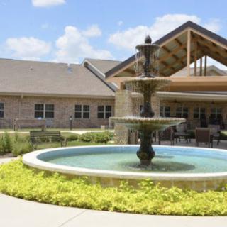 A serene outdoor setting featuring a beautiful fountain in front of a well-designed residential building.