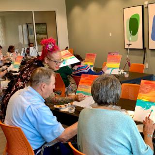Seniors participating in a painting class, expressing their creativity with colorful canvases.