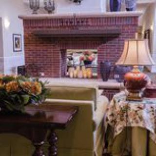 A cozy living room with a brick fireplace and floral decorations.