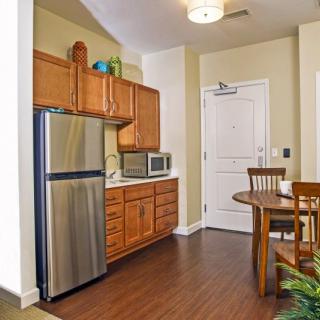 A cozy apartment kitchen with wooden cabinets, a stainless steel refrigerator, and a small dining area.