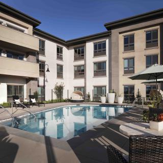 A modern apartment complex featuring an outdoor swimming pool and patio area.