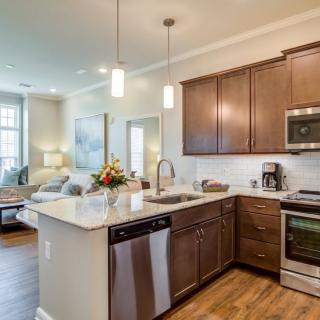 A modern open-concept kitchen with wood cabinets and stainless steel appliances, seamlessly connected to the living area.