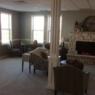 A cozy living room with a fireplace and several chairs around the area.