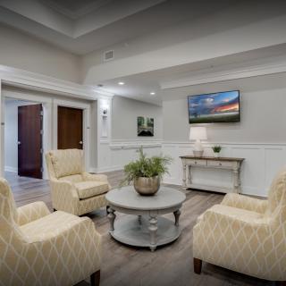A cozy lounge area with comfortable chairs, a round coffee table, and a wall-mounted television.