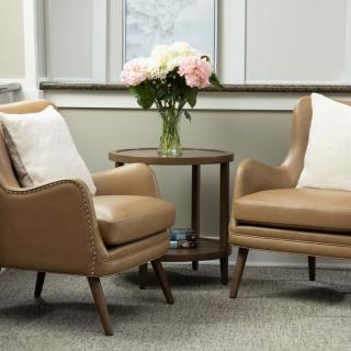A cozy living room setup with two brown armchairs, a small round table, and a vase of flowers.