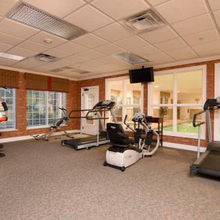 A well-lit gym room featuring exercise equipment like treadmills and stationary bikes.