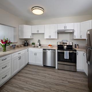 A modern kitchen with white cabinets and stainless steel appliances.