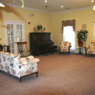 A cozy living room with floral-patterned furniture and a piano.